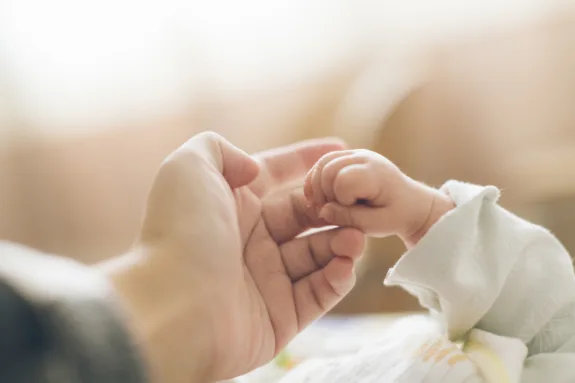 newborn baby hand holding parent's finger