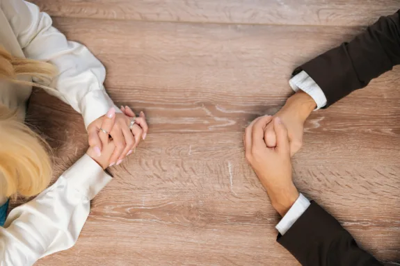 Closeup top view of clasped female and male hands negotiate at table